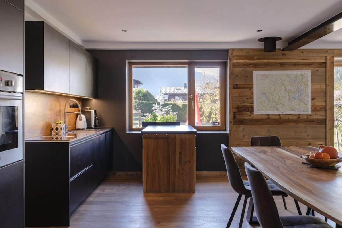 A kitchen with black cabinets and a wooden table