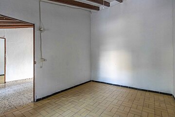 An empty room with a tiled floor and white walls