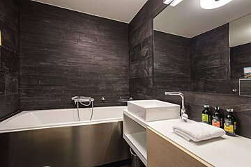 A bathroom with a stainless steel sink and a bathtub