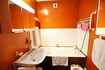 A bathroom with orange walls and a white bathtub