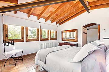 A bedroom with a wooden ceiling and a bed