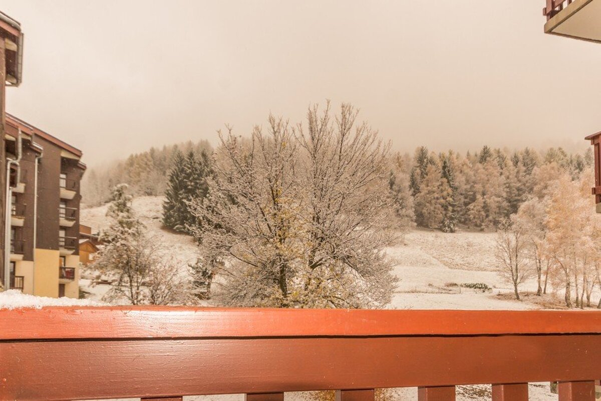 A balcony with a view of snow covered trees and buildings