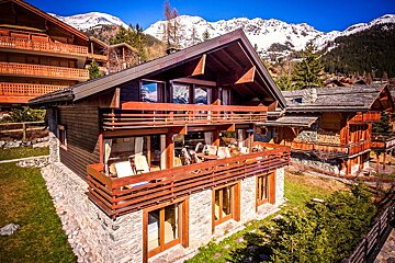 A large house with a balcony and mountains in the background