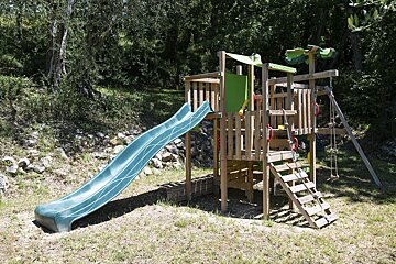 A wooden playground with a slide and swings