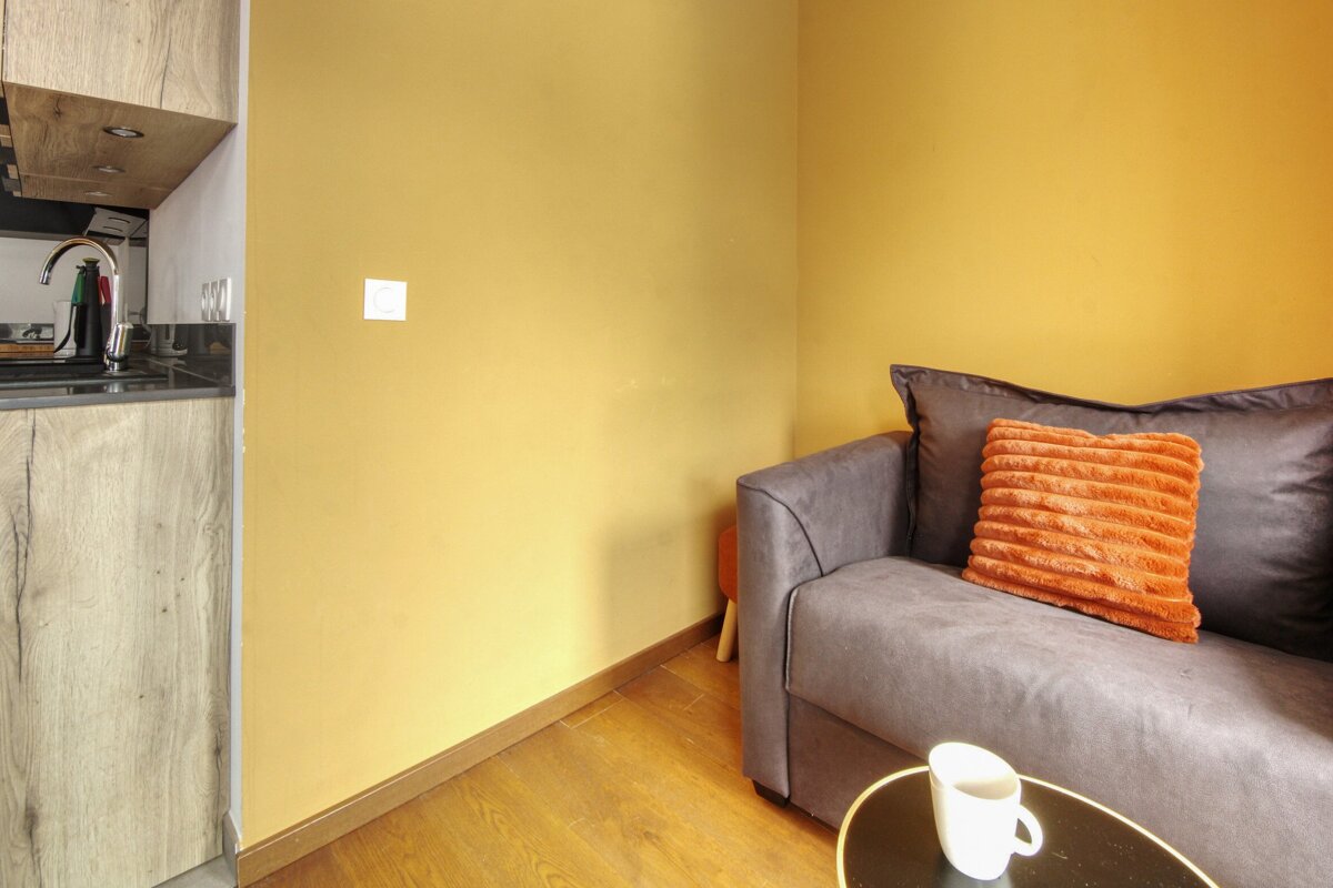 A living room with a couch and a coffee mug on a table