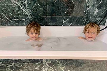 Two young boys are taking a bath together in a bathtub