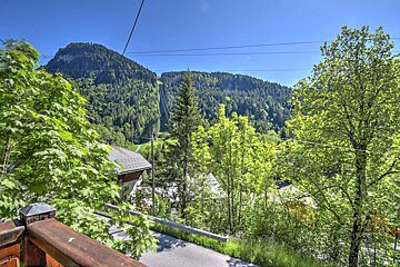A view of a mountain from a balcony with trees in the foreground