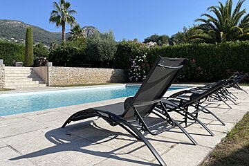 A row of black lounge chairs sit near a swimming pool