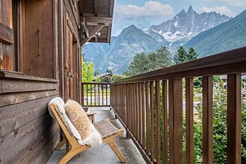 A balcony with a chair and mountains in the background