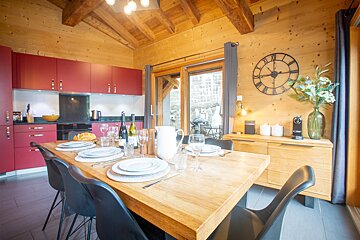 A kitchen with a clock on the wall that has roman numerals