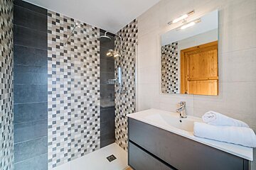 A bathroom with a walk in shower and a sink