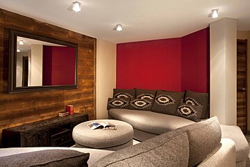 A living room with a couch and ottoman and a mirror