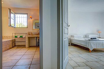 A bathroom with a sink and a bathtub next to a bedroom