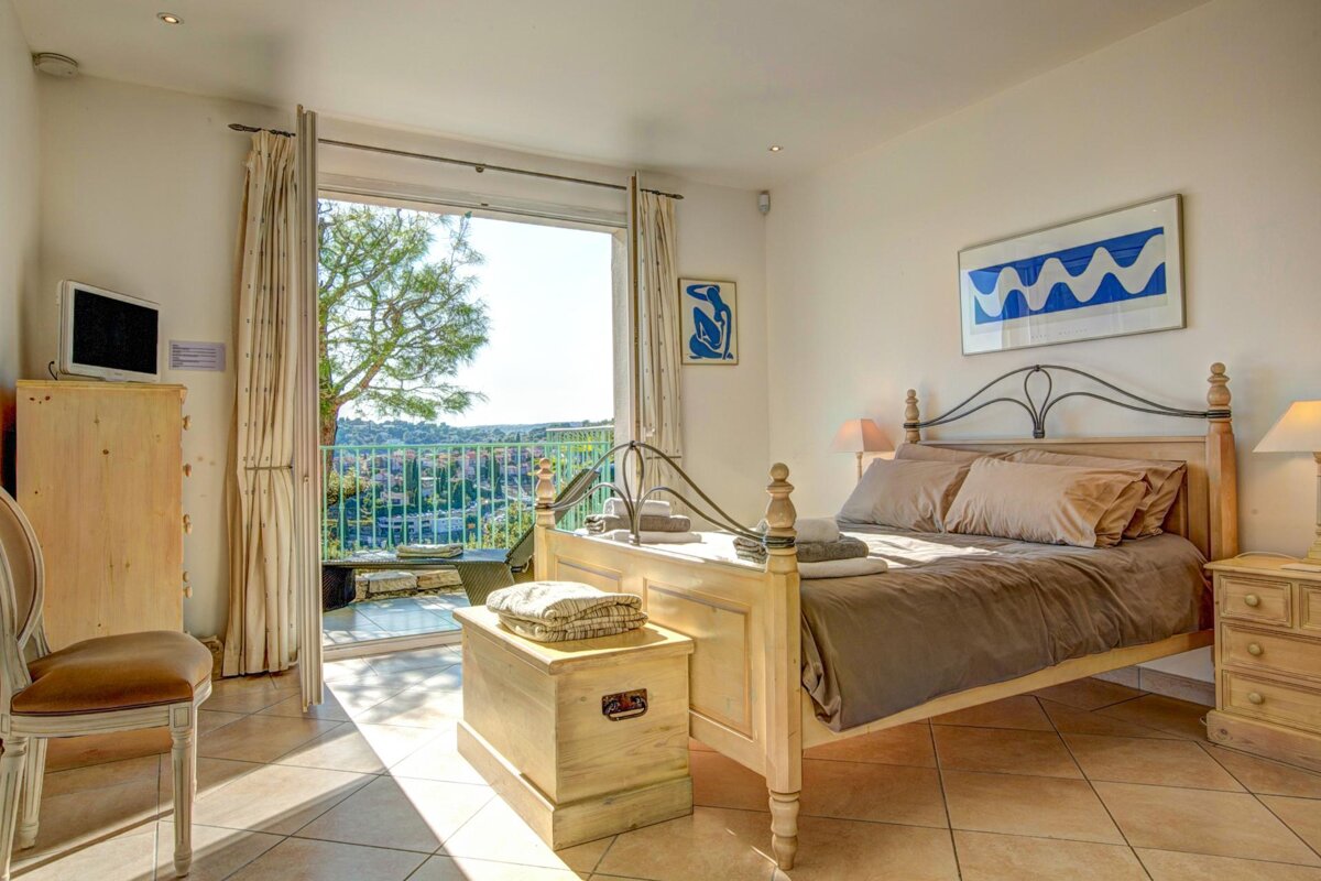 A bedroom with a bed and a blue and white painting on the wall