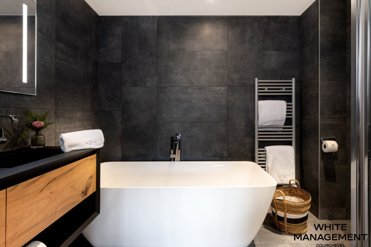 A bathroom with a bathtub and a rental designer logo