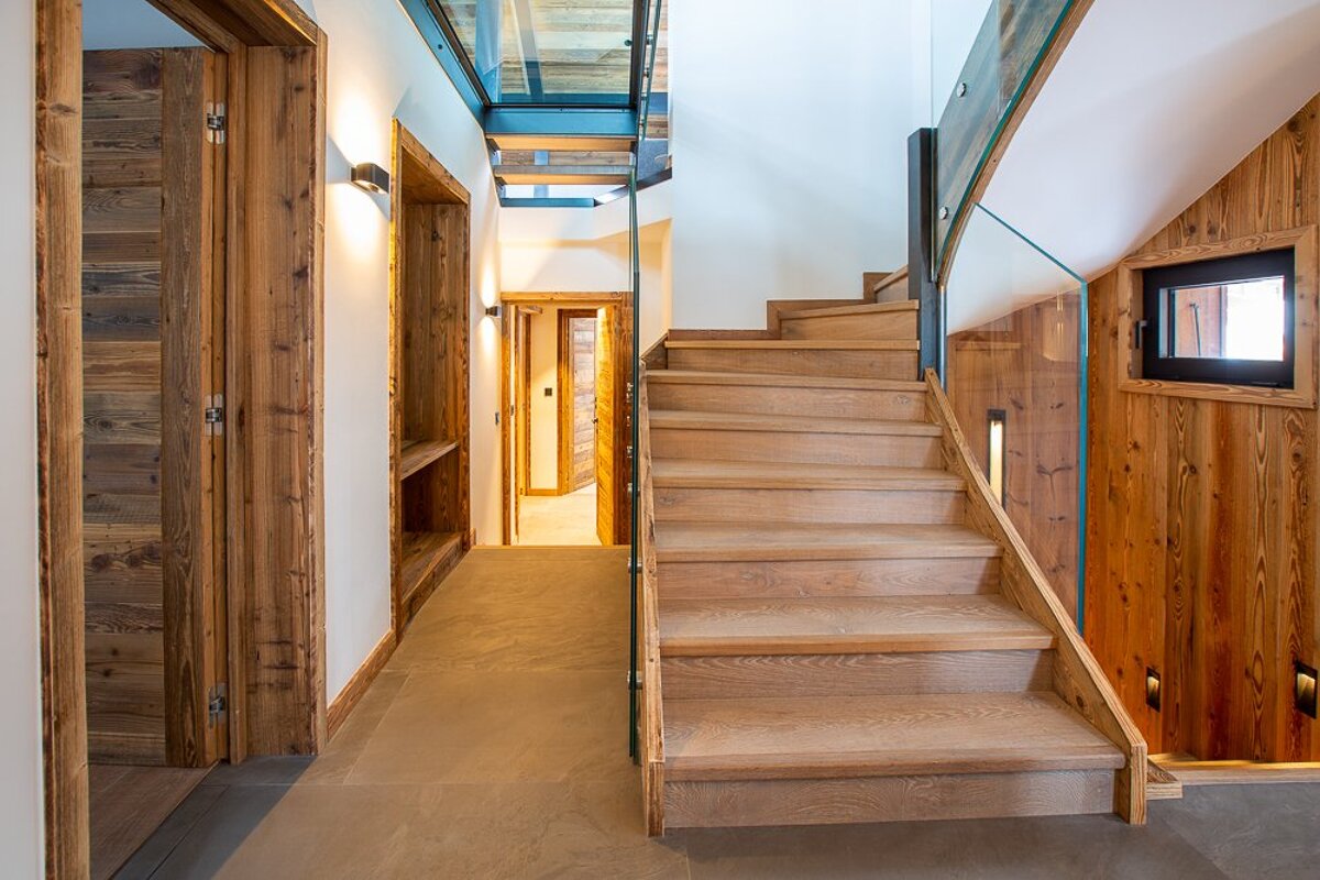 A wooden staircase with a glass railing in a hallway