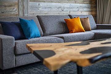 A grey couch with blue and orange pillows on it