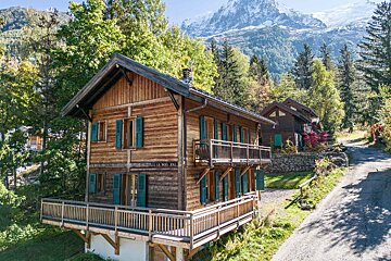 A wooden house with a balcony and a mountain in the background