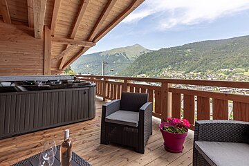 A hot tub sits on a balcony with a view of the mountains
