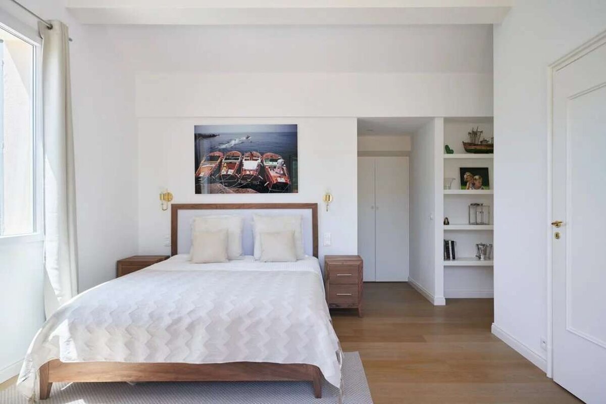 A bedroom with a bed and a picture of boats on the wall