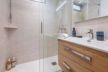 A bathroom with a walk in shower and a sink
