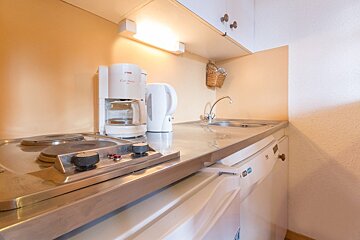 A small kitchen with a coffee maker and a kettle
