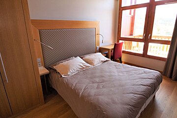 A bedroom with a bed a desk and a chair