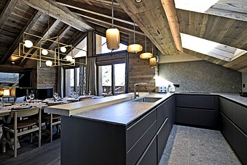 A kitchen with a dining table and chairs in the background
