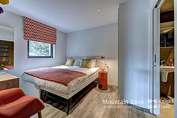 A bedroom with a bed and a chair and the words mountain base knight frank on the bottom