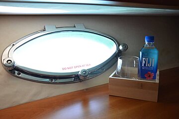 A bottle of fiji water sits next to a glass