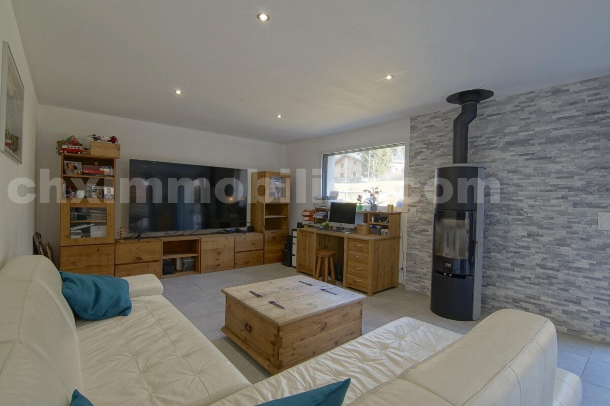 A living room with a large flat screen tv and a chimney with the website chimmobili.com in the corner