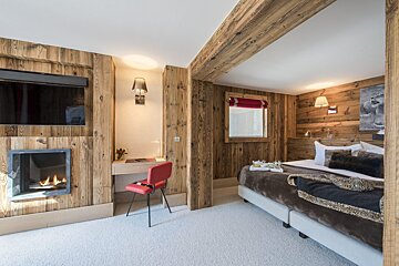 A bedroom with a large bed and a fireplace