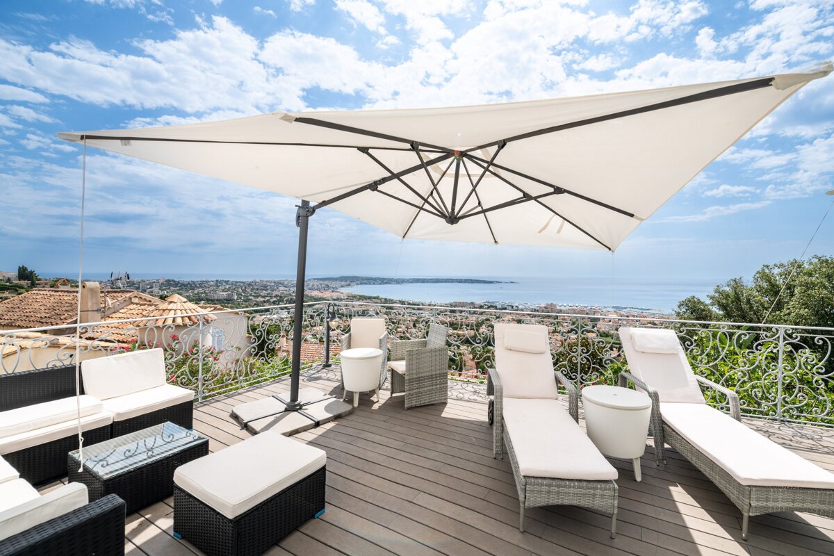 A large white umbrella is on a balcony overlooking the ocean