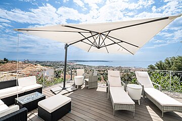 A large white umbrella is on a balcony overlooking the ocean