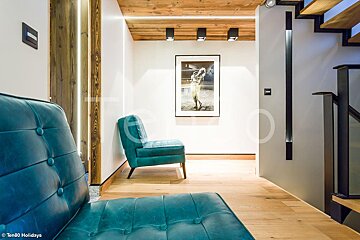 A hallway with a blue chair and a picture on the wall