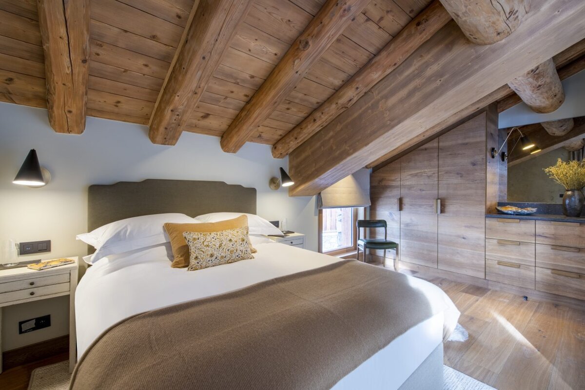 A bedroom with a wooden ceiling and a bed