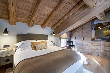 A bedroom with a wooden ceiling and a bed