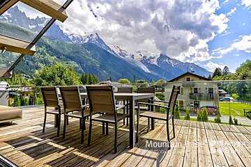 A wooden deck with a table and chairs and the word mountain on it