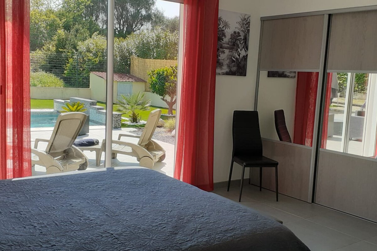 A bedroom with a sliding glass door leading to a pool