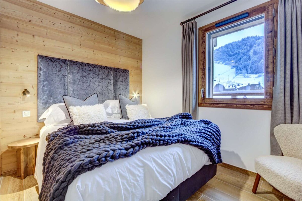 A bedroom with a bed and a window with mountains in the background