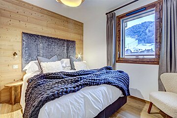 A bedroom with a bed and a window with mountains in the background