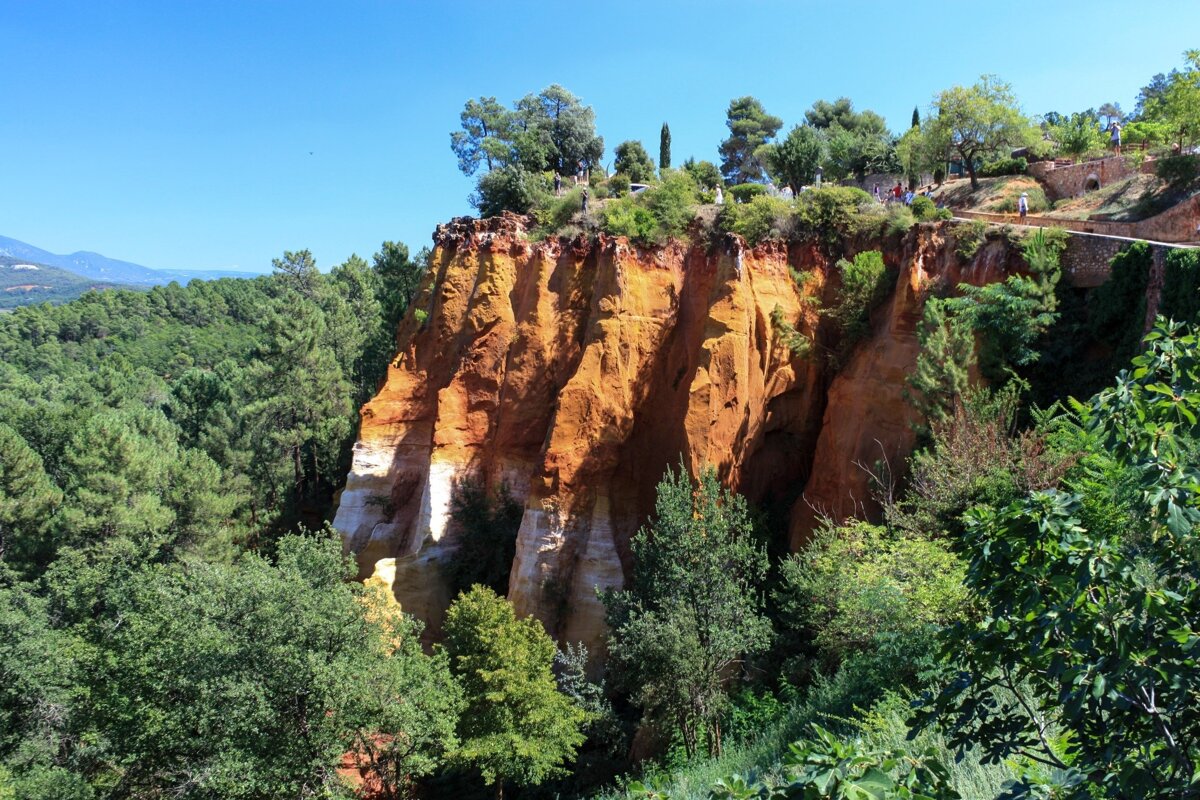 A cliff with trees on it and a blue sky in the background