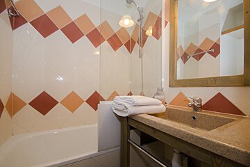 A bathroom with red and white tiles and a sink