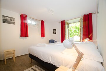 A bedroom with two beds and red curtains