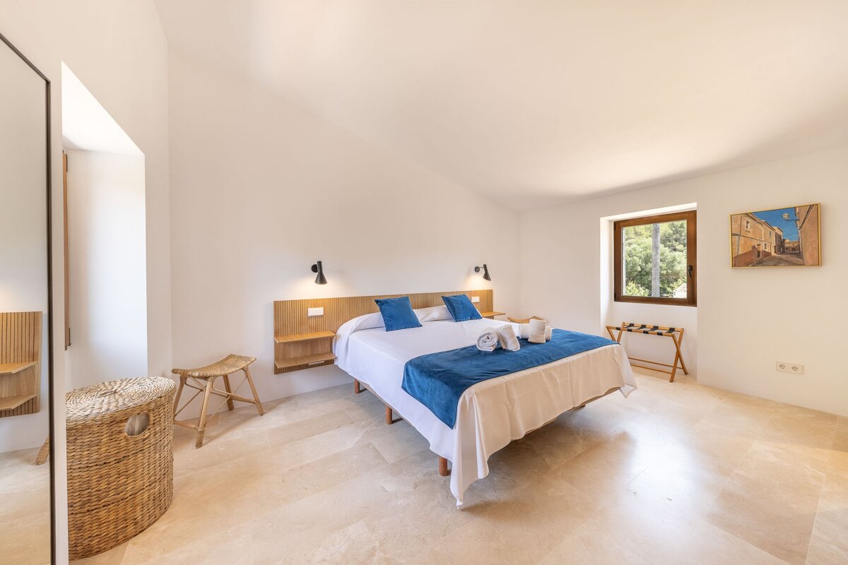 A bedroom with a large bed and a painting on the wall