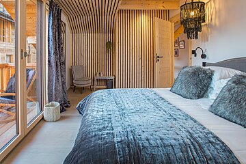 A bedroom with a large bed and a chair