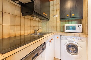A kitchen with a washing machine and a microwave