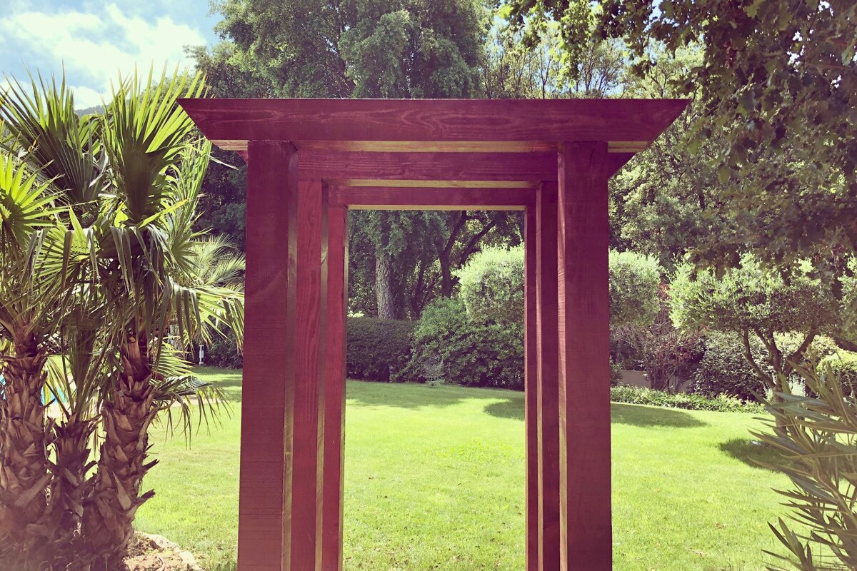 A wooden archway in the middle of a lush green field