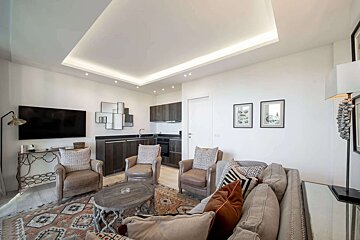 A living room with a couch two chairs and a flat screen tv