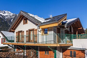 A house with a balcony and mountains in the background